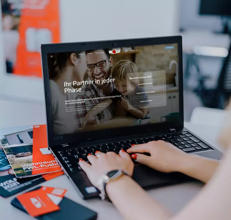 Mockup neue Webseite von WOLF Frau sitzt am Laptop und besucht WOLF Webseite