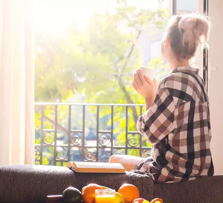 Richtig Lüften im Sommer Frau am Fenster